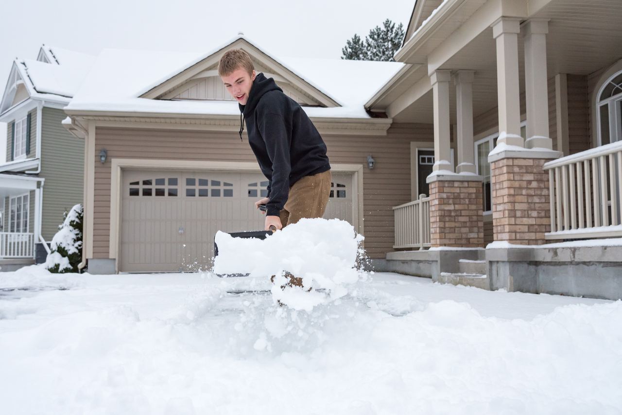 A teen shoveling a neighbor's snowy driveway